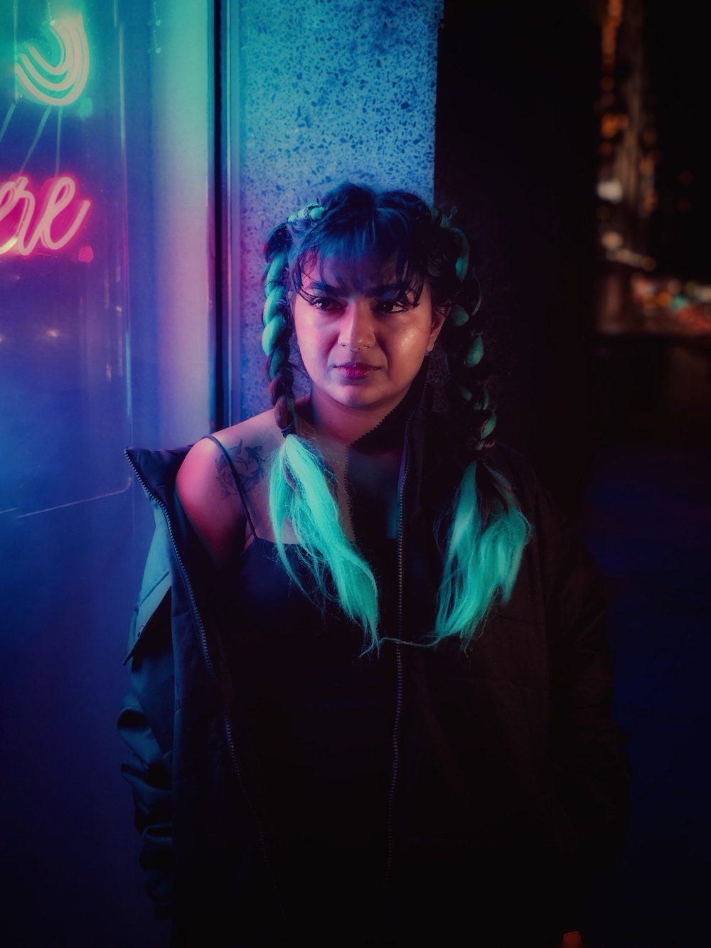 Portrait of JuLix with teal braids in neon light